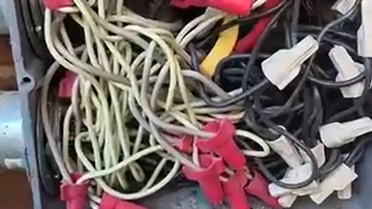 Overcrowded junction box with multiple wire-nut splices and overfilled conduit entering from below